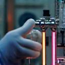 Artisan connecting a bent glass tube to a manifold for vacuum pumping and gas filling